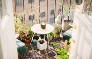 Apartment balcony with tiny table and chairs surrounded by a jungle of plants